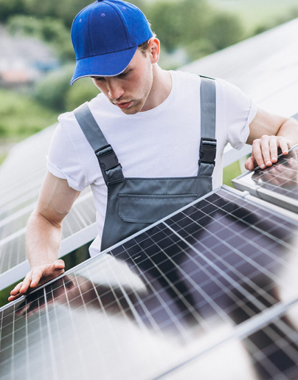 A man in overalls and a hat examining a solar panel.
